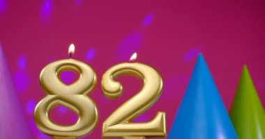 82 numaralı doğum günü pastası mumu yanıyor. Mutlu yıllar yıldönümü kutlaması konsepti. Arka planda doğum günü şapkası