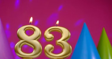 83 numaralı doğum günü pastası mumu yanıyor. Mutlu yıllar yıldönümü kutlaması konsepti. Arka planda doğum günü şapkası