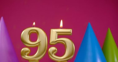 95 numaralı doğum günü pastası mumu yanıyor. Mutlu yıllar yıldönümü kutlaması konsepti. Arka planda doğum günü şapkası
