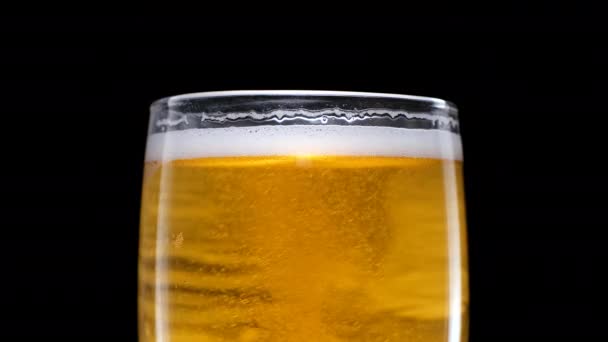 Cerveza ligera se vierte en el vidrio. Cerveza de cerveza fría en una taza de cerveza sobre un fondo negro con gotas de agua y espuma. Fondo negro aislado — Vídeos de Stock