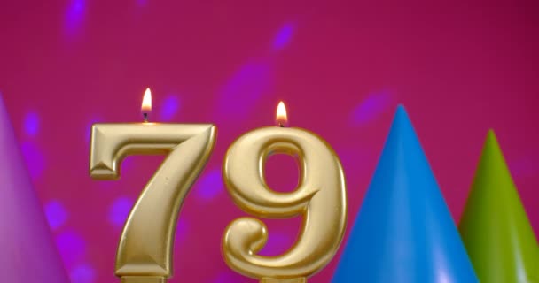 Зажигаю свечу для торта номер 79. Концепция празднования Дня Рождения. День рождения шляпа на заднем плане — стоковое видео