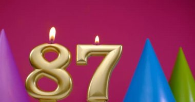 87 numaralı doğum günü pastası mumu yanıyor. Mutlu yıllar yıldönümü kutlaması konsepti. Arka planda doğum günü şapkası