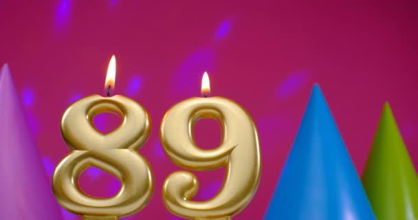Palę świeczkę urodzinową numer 89. Wszystkiego najlepszego z okazji rocznicy urodzin. Kapelusz urodzinowy w tle — Wideo stockowe