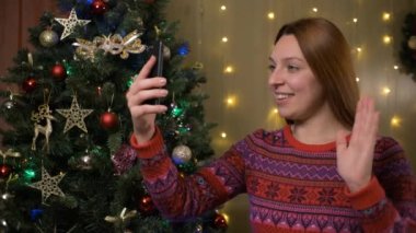 Yılbaşı Ağacı 'nın yanında Arkaplanda Parlayan Işıklarla Güzel Gülümseyen Kadın Video Mesajı Yapıyor Ya da Selfie Tatil ve Yeni Yıl Kavramı