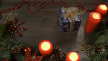 Noel hediyesi, tepeden tırnağa manzara. Kadın eli, içinde hediye olan bir kutuyu Noel ağacının dallarıyla süslenmiş bir masaya koyar.