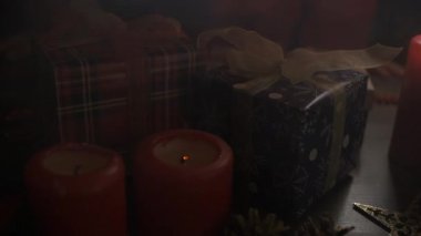 Kadın, Noel süslemeleriyle süslenmiş bir masaya mum koyuyor.