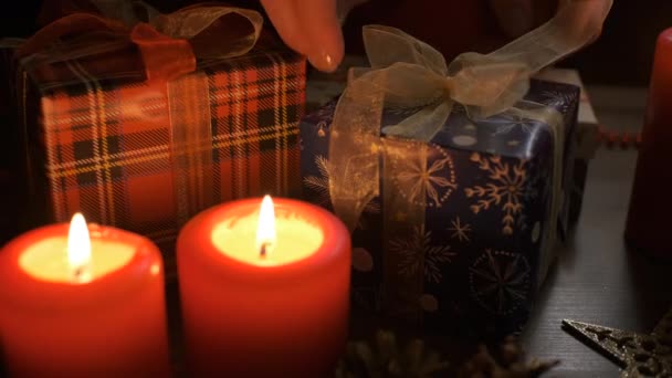 Las manos femeninas ponen y finalizan el regalo de Navidad en una mesa decorada con decoraciones navideñas. — Vídeos de Stock