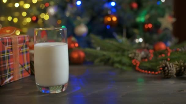 女性はミルクと木製のテーブルの上にジンジャーブレッドクッキーを置きます.クリスマスの装飾、クリスマスツリー — ストック動画