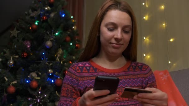 Молодая женщина делает онлайн покупки на смартфоне с помощью кредитной карты. Концепция продажи Рождества — стоковое видео