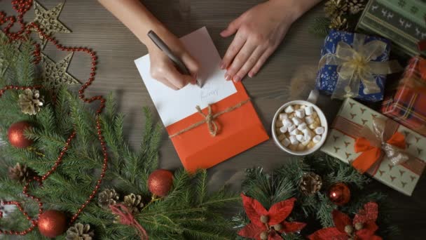 Una mujer escribe una tarjeta de Navidad con un bolígrafo — Vídeo de stock