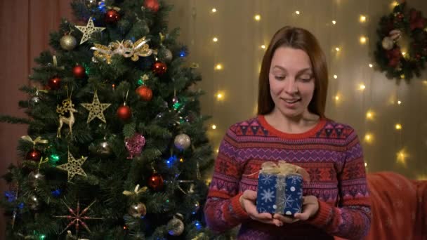 Jonge mooie vrouw shakes doos met kerstcadeau — Stockvideo