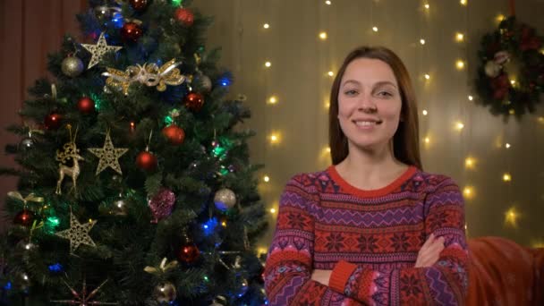 Портрет молодой женщины счастливой и взволнованной, стоящей под елкой — стоковое видео