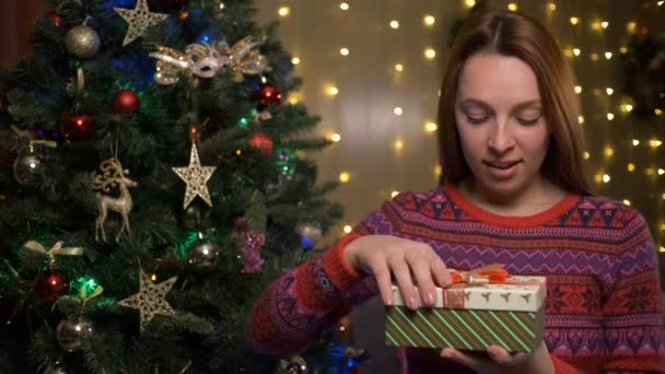 Удивительная молодая женщина смотрит на волшебный рождественский подарок в коробке — стоковое видео