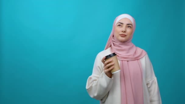 Nyugodt gyönyörű fiatal muszlim nő hidzsáb tartsa csésze kávét vagy teát. Álmodozó arab nő. Hagyományos iszlám kultúra és vallás fogalma — Stock videók