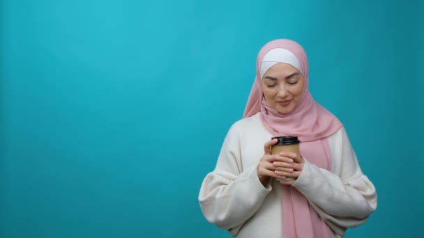 Young Muslim woman in hijab hold paper cup of coffee or tea and and dreams and thinks. Traditional Islamic culture and religion concept. Arabian religious woman — Stock Video