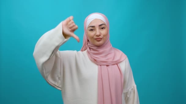 Mauvais résultat. Jeune femme musulmane mécontente dans le hijab montrant les pouces vers le bas, détestant geste — Video