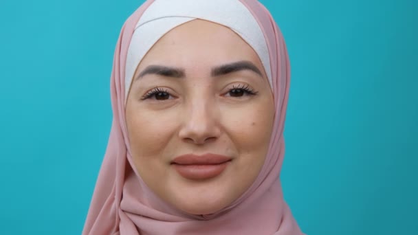 Extremt nära porträtt av ung vacker mellanösternmuslimsk kvinna klädd i hijab tittar på kameran och ler. Traditionell islamisk kultur och religionsbegrepp. — Stockvideo