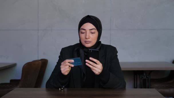 Mujer musulmana joven en hijab compras en línea en el teléfono móvil con tarjeta de crédito. Concepto de venta de tiendas, soporte de aplicaciones bancarias, e-business, finanzas de seguridad. — Vídeo de stock