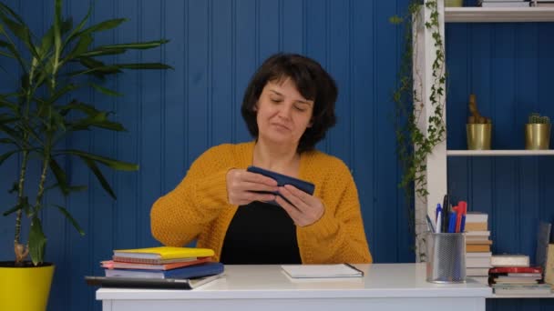 Orta yaşlı kadın evde cep telefonu oyunu oynuyor. Metaverse ve siber uzay uygulaması çevrimiçi. Kadınlar akıllı telefonlardan hoşlanırlar. Oyun ve oyun eğlencesi kavramı — Stok video