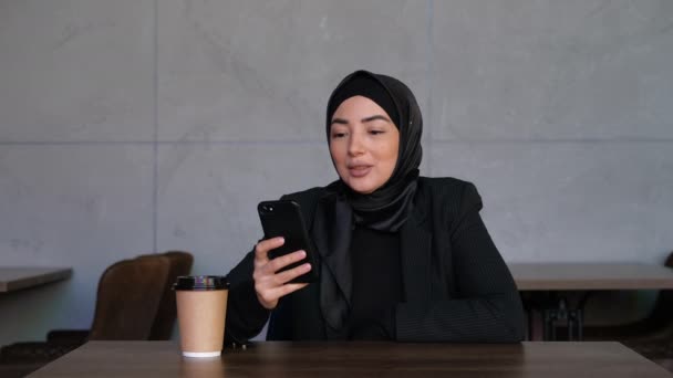 Biznesowa muzułmańska etniczna kobieta, zaangażowana w odległą rozmowę wideo, białą kawę, zdalne spotkanie z kolegami lub rodziną. Koncepcja technologii bezprzewodowej, konferencja online, rozmowa kwalifikacyjna — Wideo stockowe