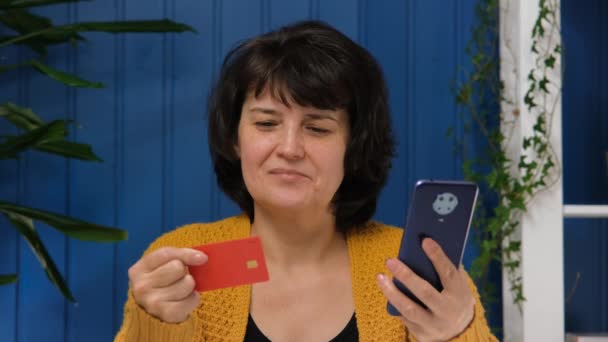 Женщина средних лет с кредитной картой, использующая смартфон для покупок в Интернете. Концепция интернет-банкинга, электронного бизнеса, онлайн-оплаты — стоковое видео