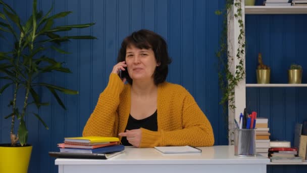 Bizneswoman w średnim wieku lub freelancer mówiący telefon komórkowy w biurze domu. Koncepcja rodzinnej rozmowy telefonicznej, komunikacji zespołowej, szczęśliwej rozmowy — Wideo stockowe