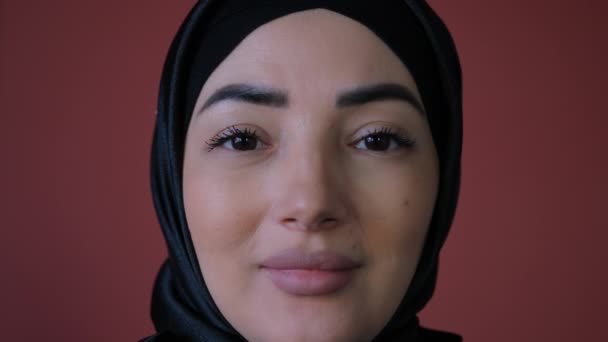 Uma visão de perto de uma mulher árabe feliz usando um hijab preto está sorrindo para a câmera de pé. Conceito tradicional de cultura e religião islâmica. — Vídeo de Stock