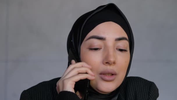 Wanita bisnis Muslim muda dalam jilbab berbicara di telepon genggam. Telepon kantor atau berbicara sedikit keluarga. Tradisional Islam budaya dan agama konsep — Stok Video