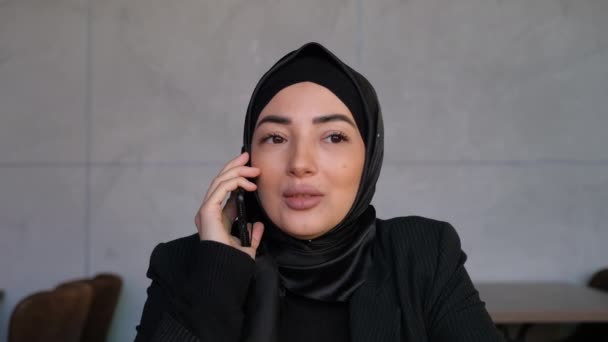 A hidzsábi fiatal muszlim nő beszél telefonon. Családi vagy üzleti hívás. Fogalom az online beszélgetés és kommunikáció. Hagyományos iszlám kultúra és vallás fogalma — Stock videók