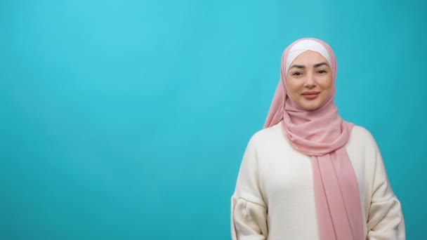 Mulher muçulmana árabe em hijab tradicional olhando direto para a câmera e sorrindo. Close up de fêmea com sorriso. Cachecol árabe. Cultura islâmica. Estúdio isolado tiro — Vídeo de Stock