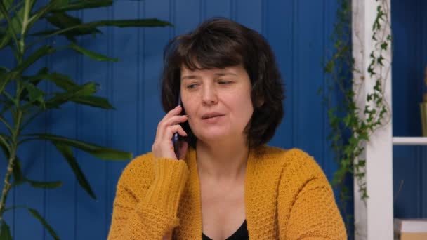 Zakenvrouw van middelbare leeftijd die thuis op smartphone praat. Zakelijk of familie gelukkig telefoontje. Gelukkige vrouwelijke klant maakt mobiel bellen. Bestelbon levering concept — Stockvideo