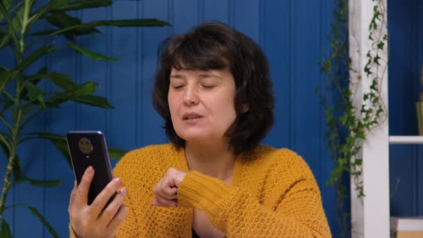 Medelålders kvinna pratar på videosamtal med mobiltelefon hemma. Videochatt jobbintervju eller distansutbildning med online lärare koncept. — Stockvideo