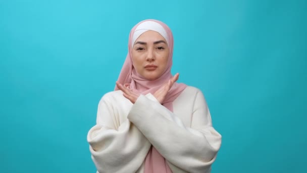 Мусульманская женщина скрещивает руки в стоп-жесте, предупреждает о проблемах, отступает с негативным выражением. Равноправие, разнообразие, феминизм, раса, расизм, права человека, защита, дискриминация — стоковое видео