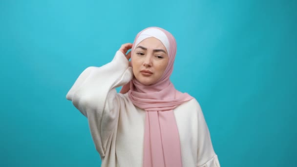 Mujer musulmana joven en hiyab posando aislada en un estudio de fondo azul. Concepto de estilo de vida. Ponga la mano en la cabeza mantenga el dedo índice hacia arriba con una gran idea nueva — Vídeos de Stock