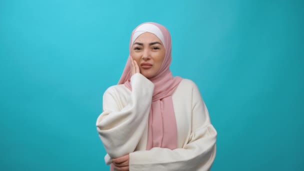 Problemy z zębami. Niezdrowa młoda muzułmanka w hidżabie dotykająca obolałego policzka, cierpiąca na straszny ból zęba, straszny ból jamy ustnej i choroby dziąseł. kryty izolowane studio strzał — Wideo stockowe