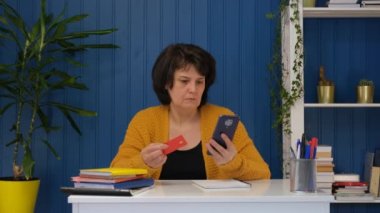 Orta yaşlı bir kadın akıllı telefondan alışveriş yapıyor, kredi kartı numarasını yazıyor ve alışverişi iptal ediyor. Para gönderme hatası ya da kartta para yok ya da karttan para çalma hatası