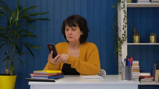 Mujer de mediana edad usando el teléfono en casa. Los mensajes de texto comparten aplicaciones de mensajes en las redes sociales. Concepto de comunicación en línea, leer las redes sociales. — Vídeos de Stock