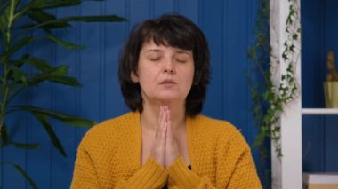 Orta yaşlı bir kadın sorunlarla ilgili yardım istiyor ya da işine odaklanmış bir zihin, dindar bir kadın gözleri kapalı dua ediyor. Dua ve umut kavramı