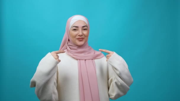 Wow, kau memilihku. Wanita Muslim muda yang terkejut dalam jilbab menunjuk dirinya sendiri dan melihat dengan takjub, terkejut tentang keberhasilan, prestasi yang luar biasa. Rekaman studio yang terisolasi — Stok Video