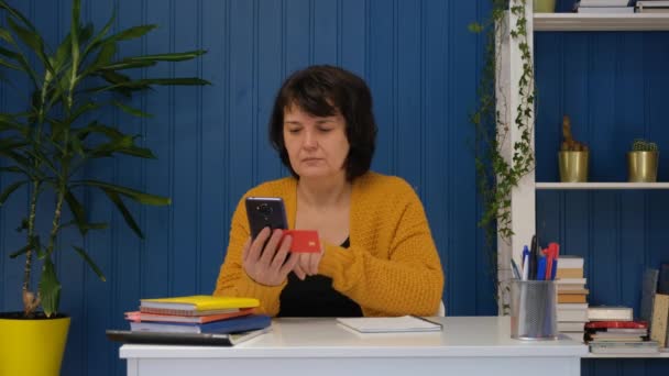 Femme d'âge moyen faisant des achats en ligne sur téléphone mobile avec carte de crédit — Video