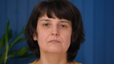 Evinde kameraya bakan orta yaşlı güzel bir kadın. Görünüm portresini kapat