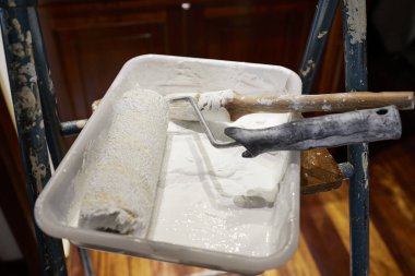 Painter's bucket. White paint, brush and paint roller