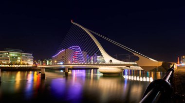 Samuel Beckett 'in Dublin' deki köprüsünün gece fotoğrafı yakınlardaki binaların ve fenerlerin ışığıyla güzelce aydınlatılmış.