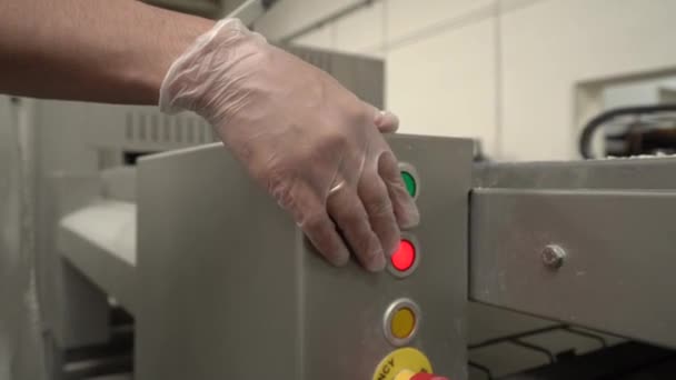 A womans hand in a latex glove presses the start button on production equipment — Stock Video