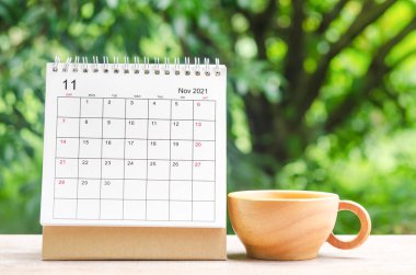 Doğanın arka planındaki ahşap masa üzerinde organizatörün planlaması ve hatırlatması için Kasım 2021 takvim masası.
