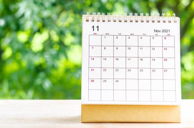 Doğanın arka planındaki ahşap masa üzerinde organizatörün planlaması ve hatırlatması için Kasım 2021 takvim masası.