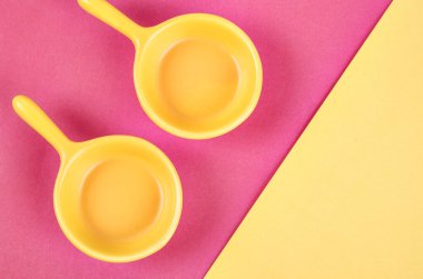 Pembe ve sarı arkaplanda boş sarı bardaklar.