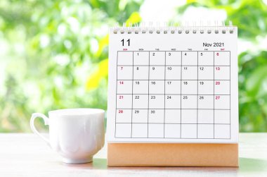 Doğanın arka planındaki ahşap masa üzerinde organizatörün planlaması ve hatırlatması için Kasım 2021 takvim masası.