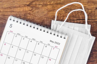 Tahta arka planda cerrahi maske takılı Mayıs 2022 masa takvimi..