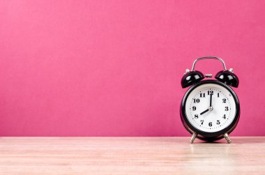 Ahşap tezgahta pembe arkaplan ile geri alarm saati.